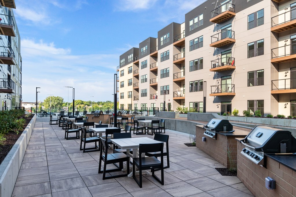 an outdoor patio with tables and chairs and an apartment building in the background